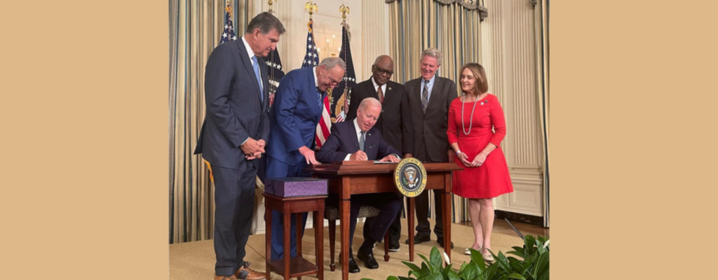 President Biden signs law while legislators watch at the White House