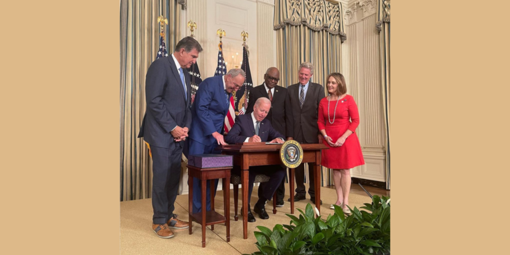 President Biden signs law while legislators watch at the White House