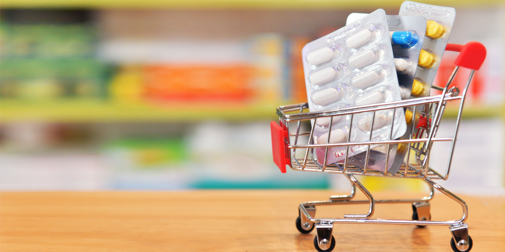 Image of miniature shopping cart and medicine blister packs